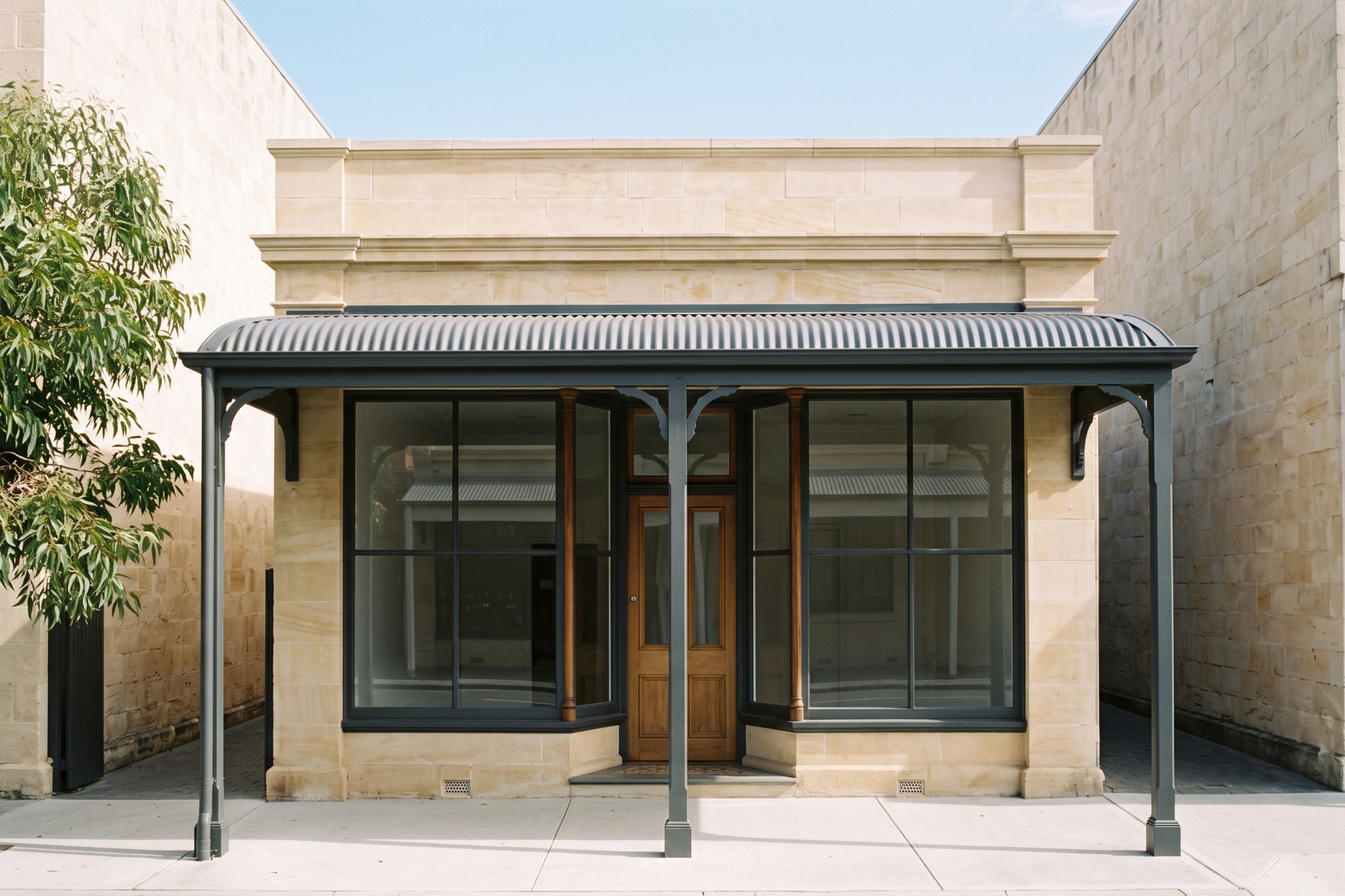The practice's restored limestone shopfront, two timber windows either side of the door under a veranda