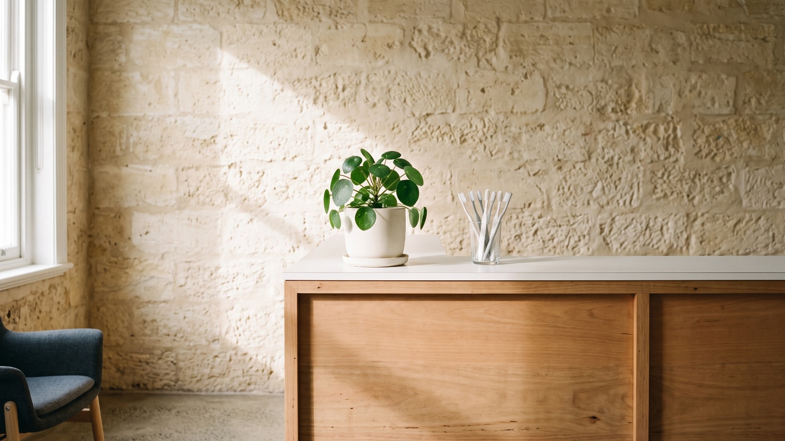 The reception counter in pale jarrah, with a plant and a glass of new toothbrushes